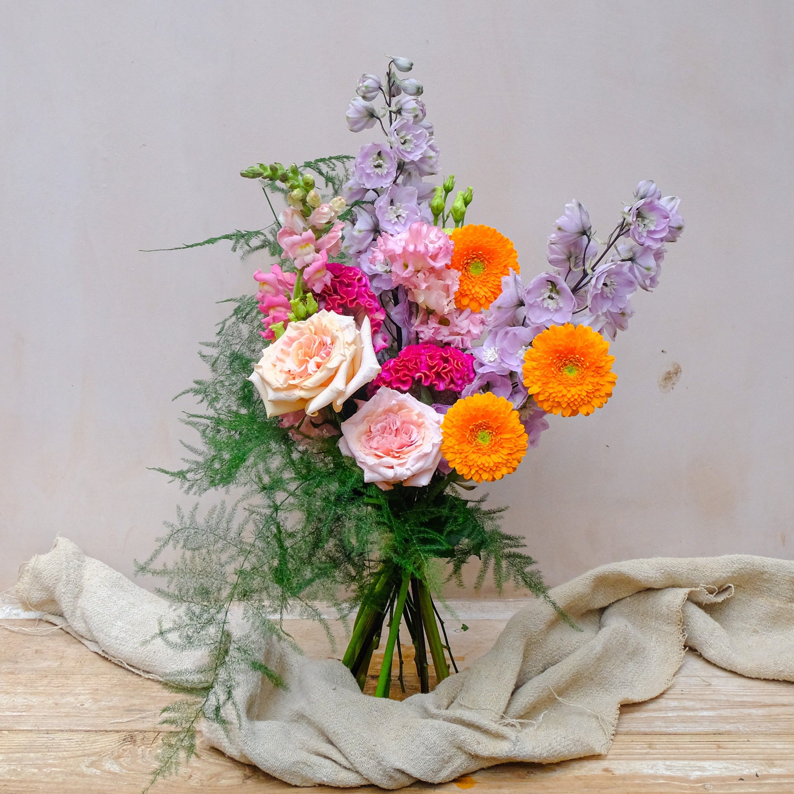 Colourful fresh flowers bouquet with purple delphinium, orange gerbera and ppink snadragon