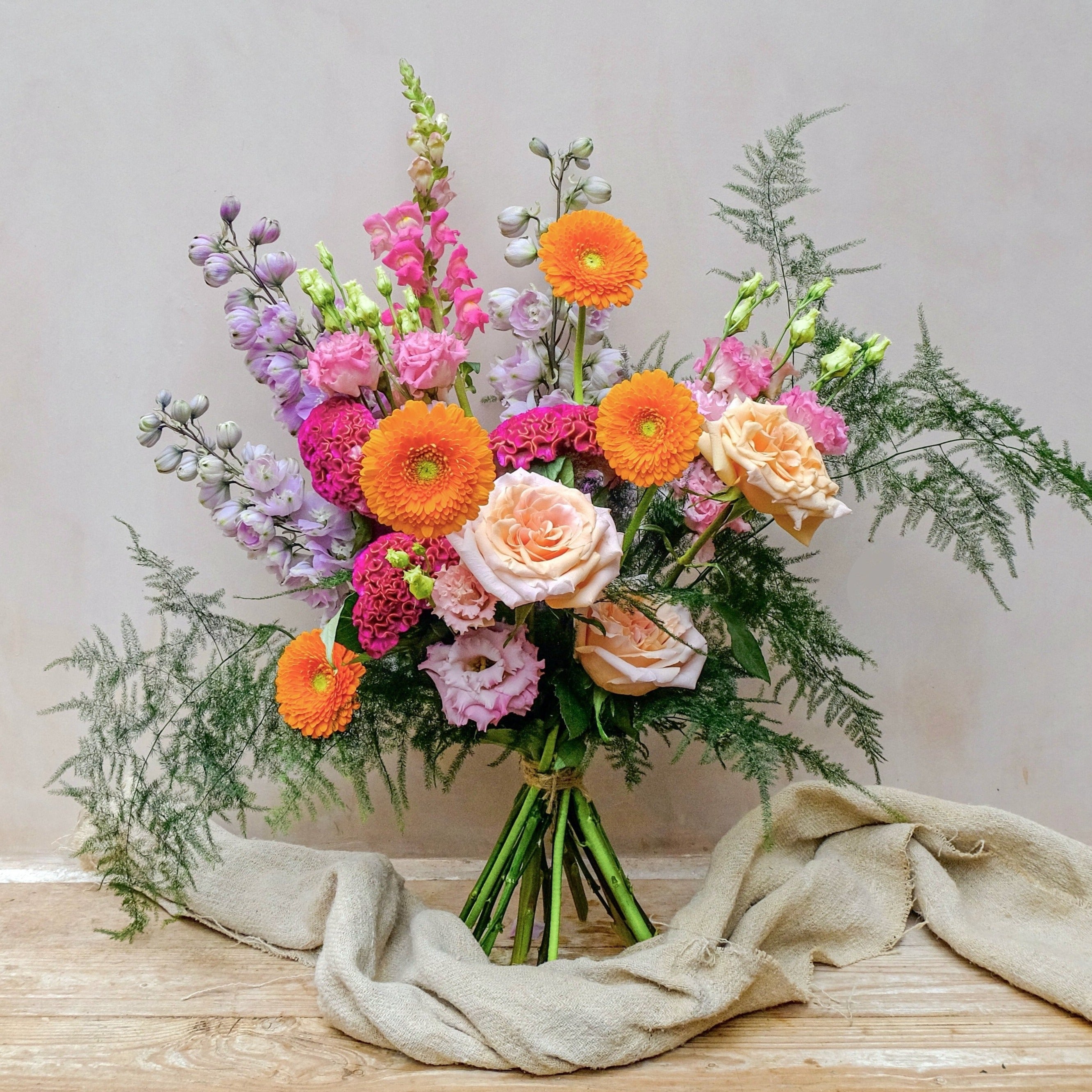 Colourful fresh flowers bouquet with purple delphinium, orange gerbera and ppink snadragon
