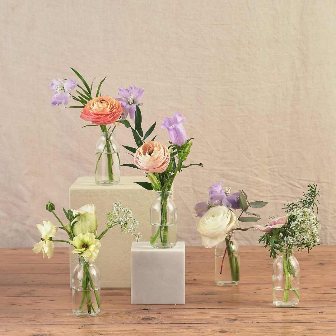 pastel wildflowers in milk bottles to decorate wedding venue and dining table