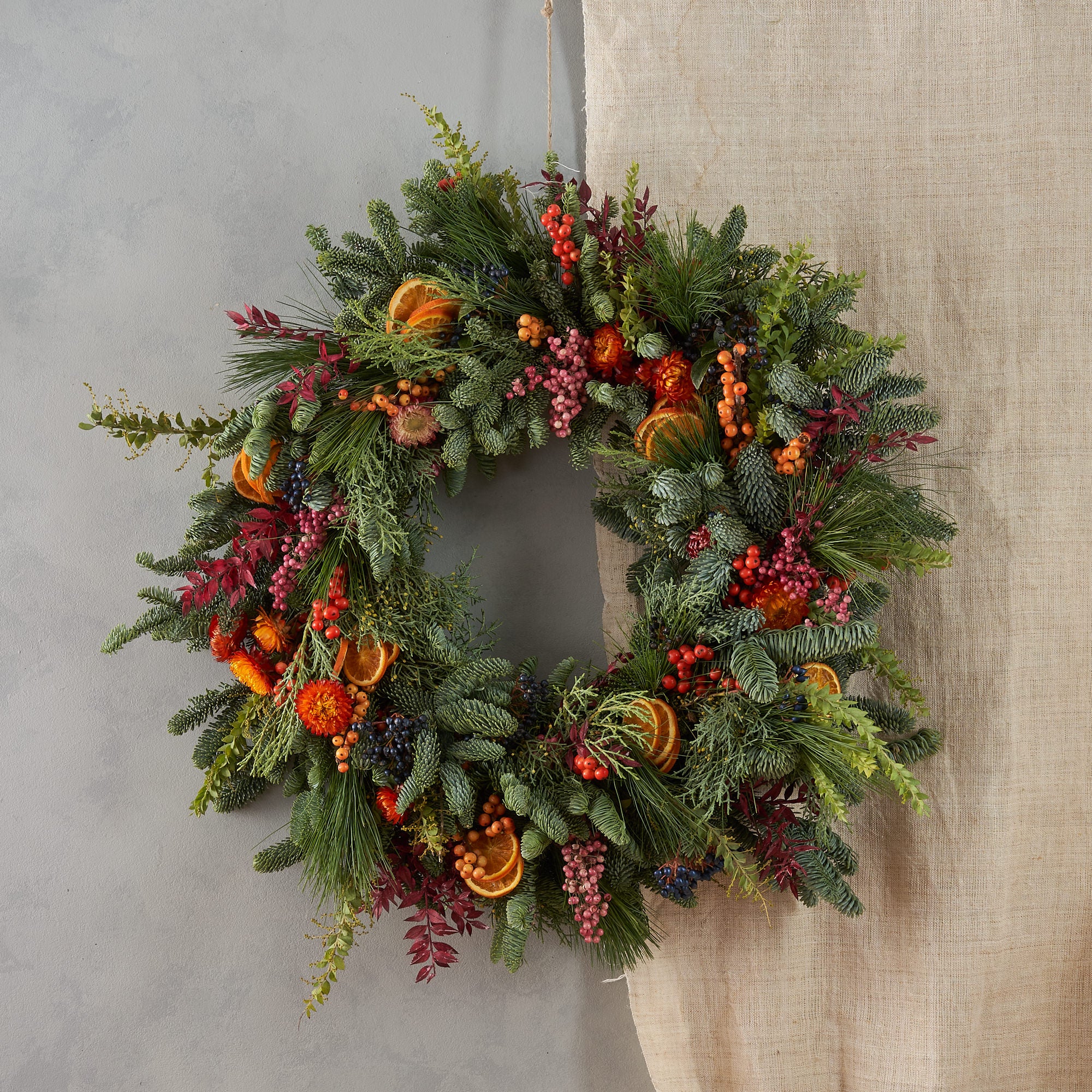 Christmas wreath with dried orange, red berries and dried flowers arranged in a contemporary modern style by Botanique Workshop London