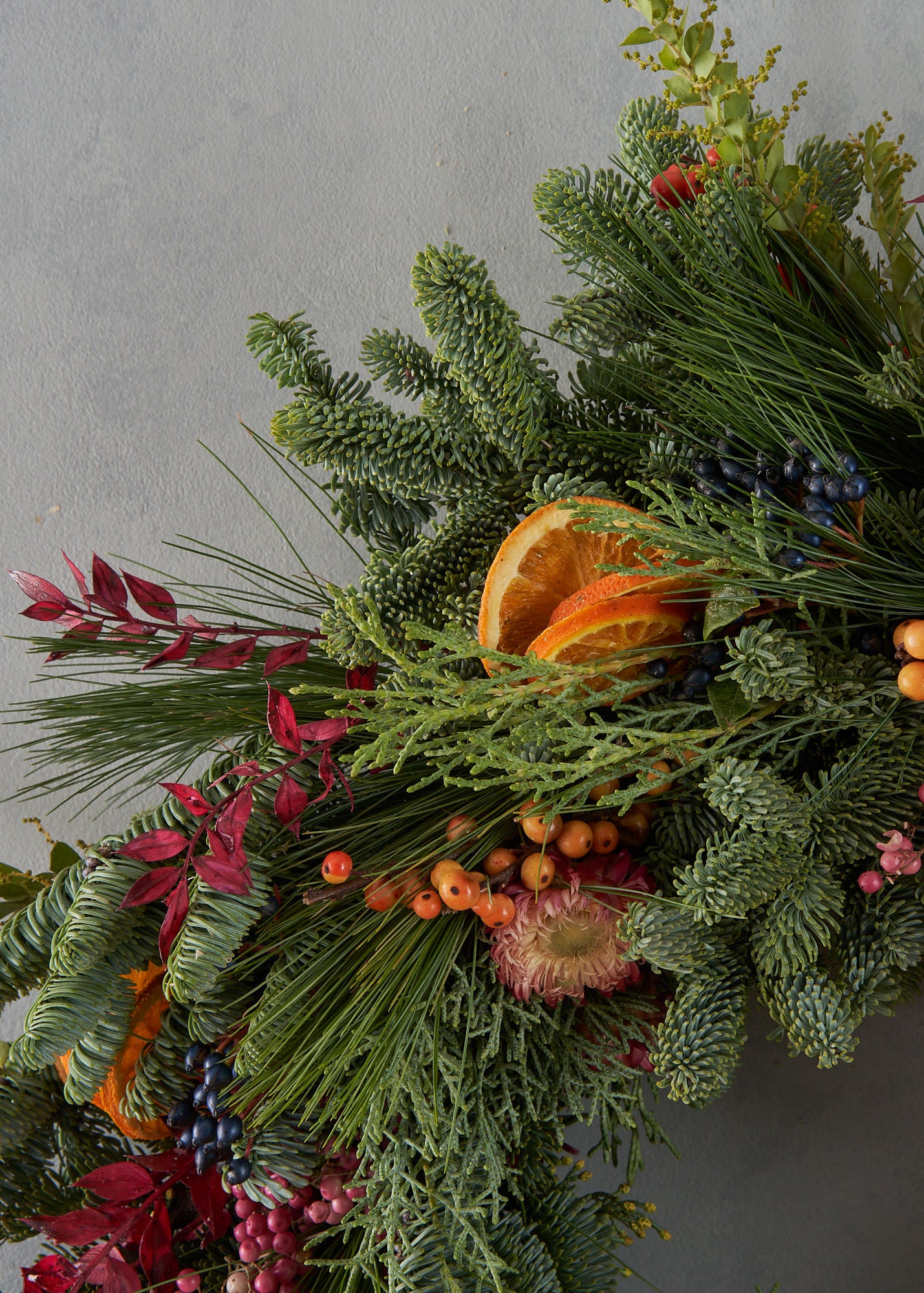 Christmas wreath with dried orange, red berries and dried flowers arranged in a contemporary modern style by Botanique Workshop London