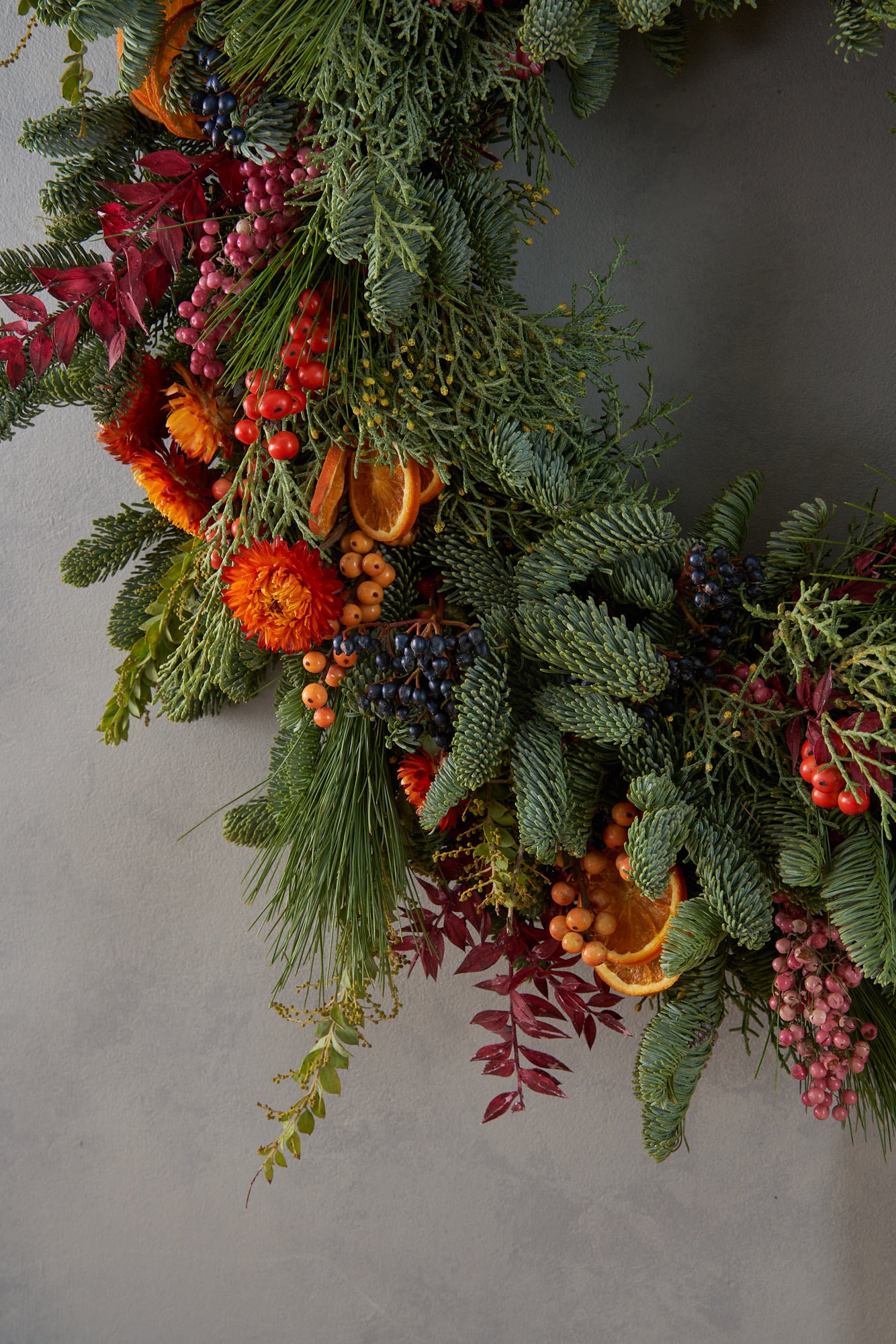 Christmas wreath with dried orange, red berries and dried flowers arranged in a contemporary modern style by Botanique Workshop London