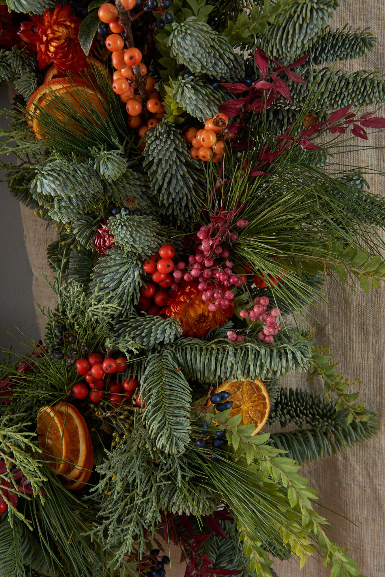 Christmas wreath with dried orange, red berries and dried flowers arranged in a contemporary modern style by Botanique Workshop London