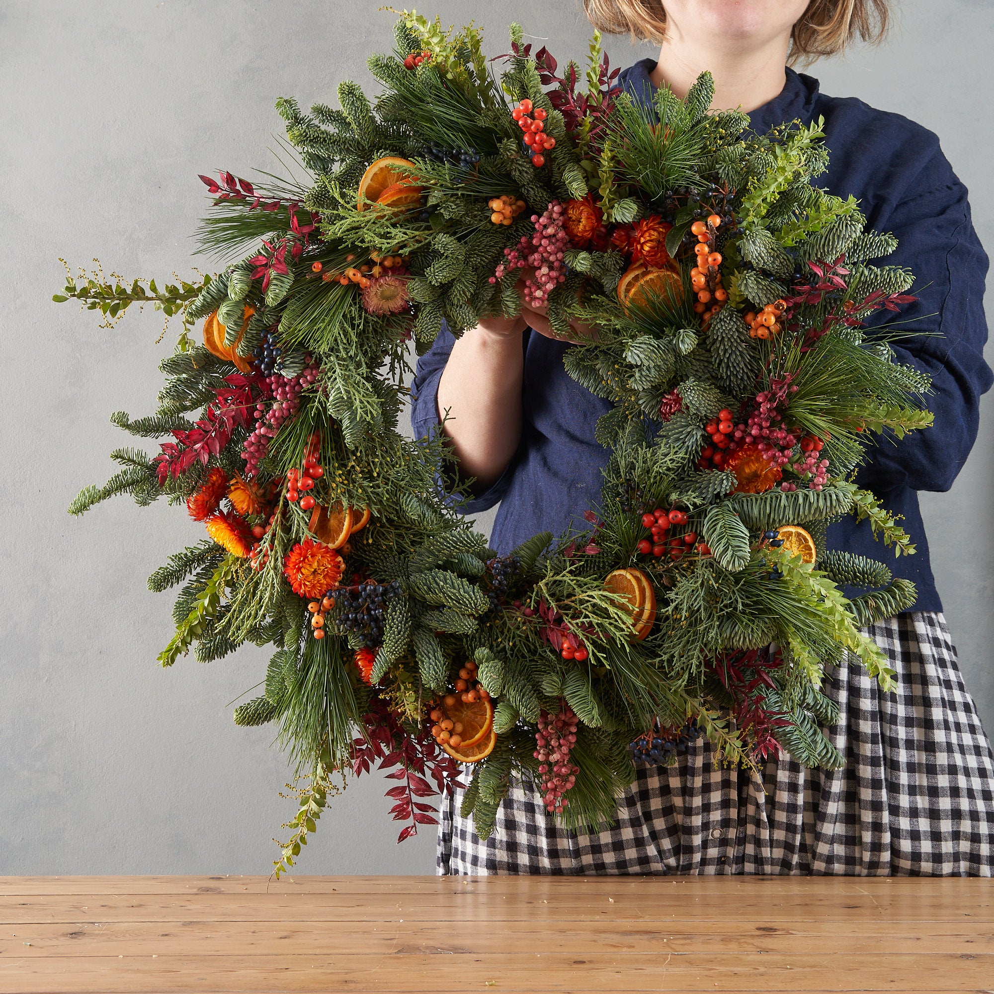 Christmas wreath with dried orange, red berries and dried flowers arranged in a contemporary modern style by Botanique Workshop London