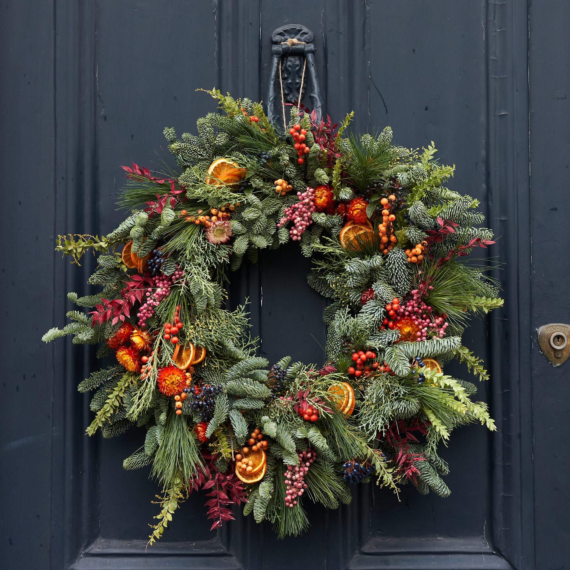 Christmas wreath with dried orange, red berries and dried flowers arranged in a contemporary modern style by Botanique Workshop London