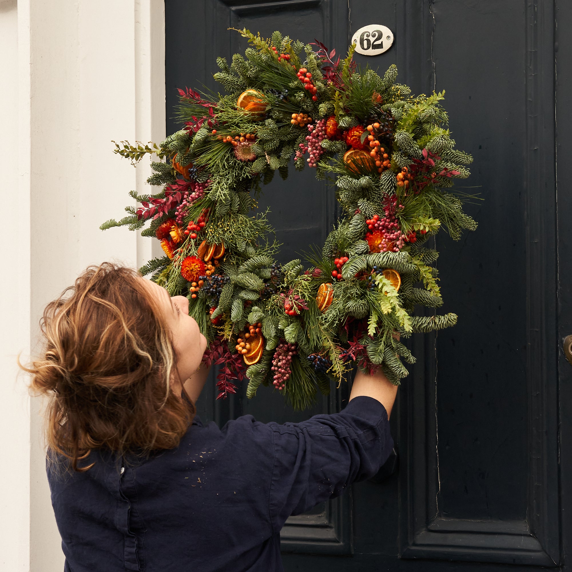 Christmas wreath with dried orange, red berries and dried flowers arranged in a contemporary modern style by Botanique Workshop London