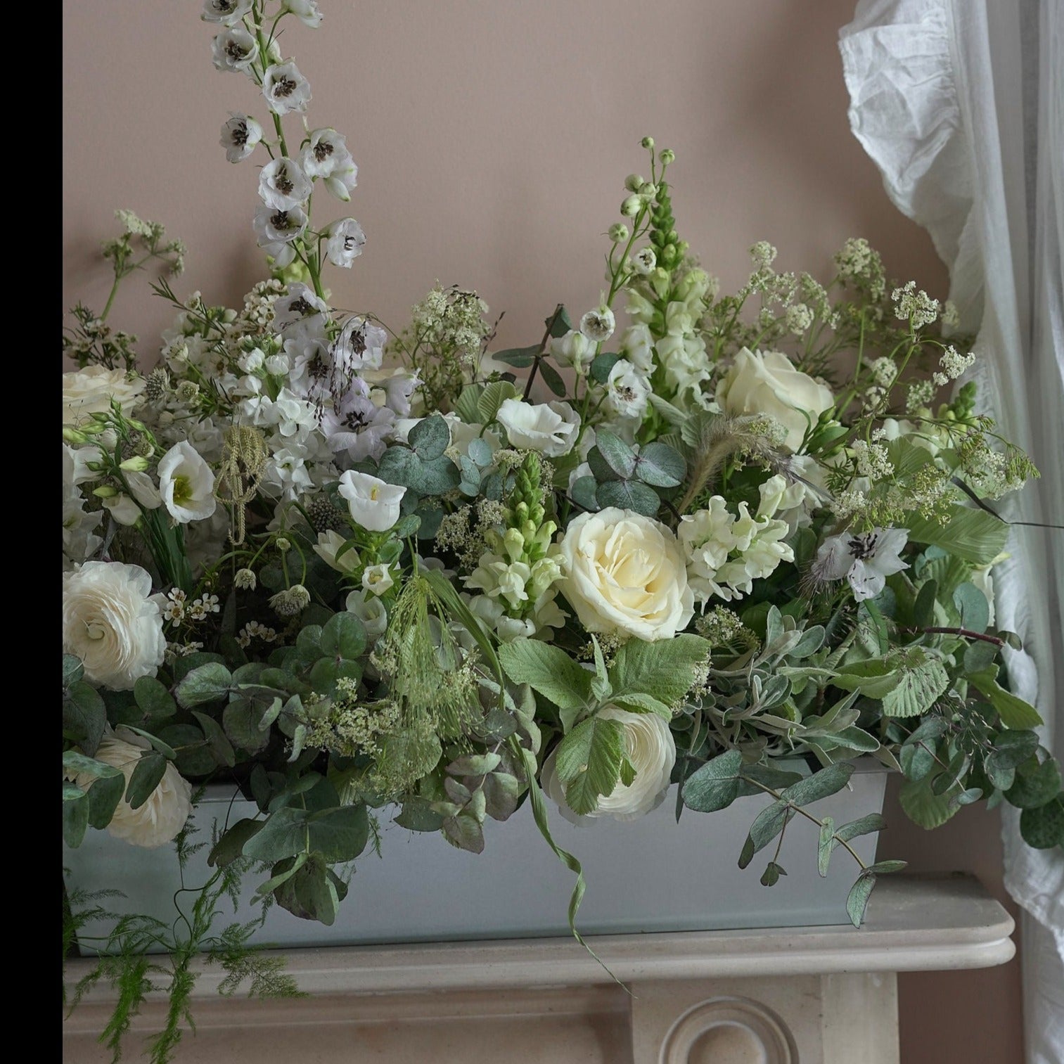 classic white and green foliage trough arrangement to decorate wedding venues and mantlepieces